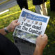 Photo of man reading Capital Gazette one day after a mass shooting at the newspaper