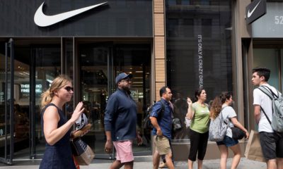Photo of people passing in front of a Nike store in New York