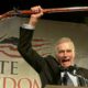 Photo of National Rifle Association President Charlton Heston holding up a rifle