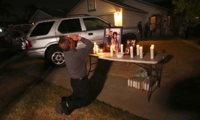 Photo of Neej Xiong, uncle of shooting victim Kou Xiong, praying in front of a memorial during a candle light vigil in Fresno