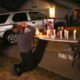 Photo of Neej Xiong, uncle of shooting victim Kou Xiong, praying in front of a memorial during a candle light vigil in Fresno