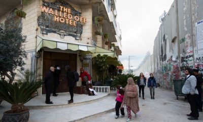Photo of people walking by "The Walled Off Hotel"