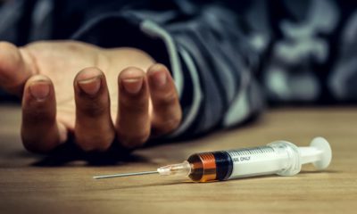 Photo of a man's hand and a heroin syringe