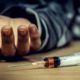 Photo of a man's hand and a heroin syringe