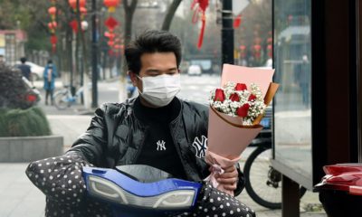 Photo of a man wearing a face mask carrying a bouquet
