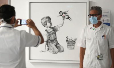 Photo of health care workers in front of a new artwork by Banksy