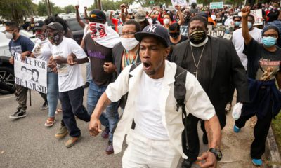 Photo of a group of people marching from the Glynn County Courthouse in downtown to a police station