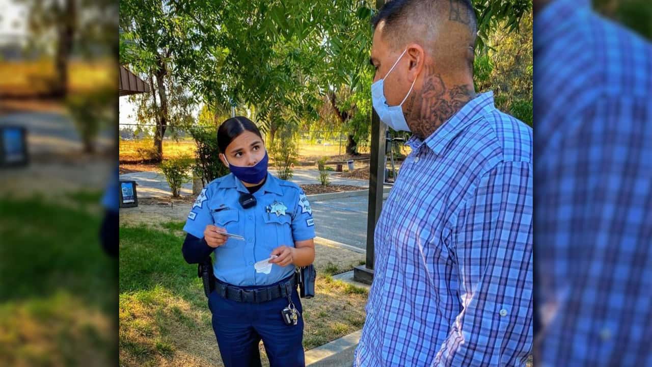 Image of a masked Fresno police officer talking to a masked resident